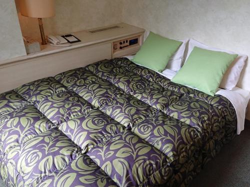丰中A.P酒店的一张位于酒店客房的床位,配有绿色枕头