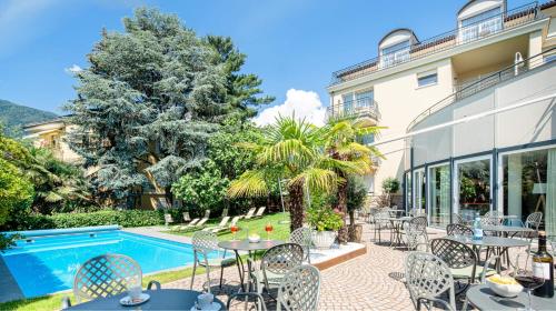 梅拉诺Hotel Villa Laurus的游泳池旁带桌椅的天井