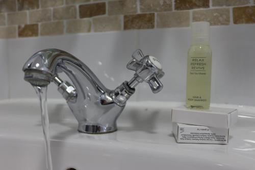 盖尔洛赫阿罗柴尔定制酒店的水槽,配有水龙头和一瓶肥皂