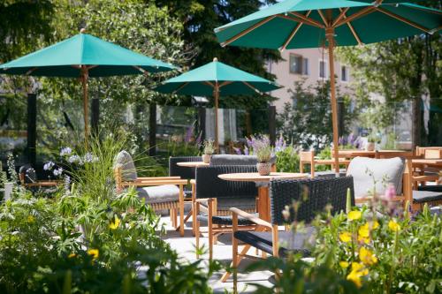 蓬特雷西纳Hotel Walther - Relais & Châteaux的一个带桌椅和遮阳伞的庭院。