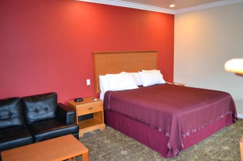 半月湾The Miramar Inn & Suites的酒店客房,配有床和皮椅