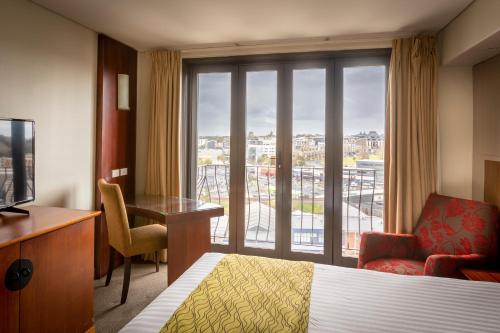 奥克兰国敦酒店的配有一张床、一张书桌和一扇窗户的酒店客房