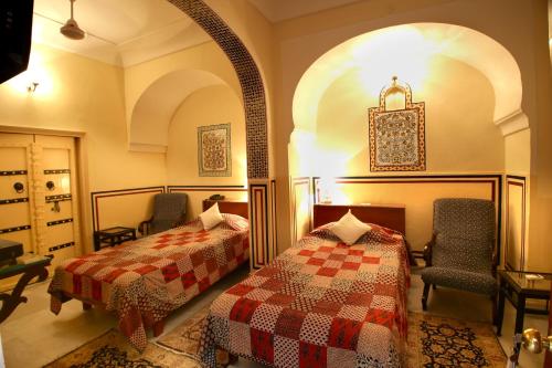 斋浦尔卡图哈维丽酒店的一间卧室配有两张床和椅子。