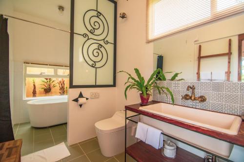 今归仁村苏莫斯住宿加早餐旅馆的带浴缸、卫生间和盥洗盆的浴室
