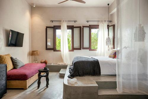 林都斯Casita Casita Lindos - Adults Only的一间卧室配有一张床、一张沙发和窗户。
