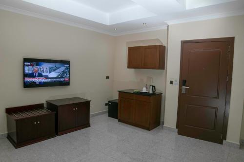 阿克拉君主酒店的一间墙上配有电视的房间和一扇门