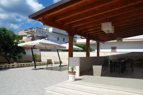 普尔萨诺Villa Cohiba - 700m dal mare的庭院配有遮阳伞和桌椅。