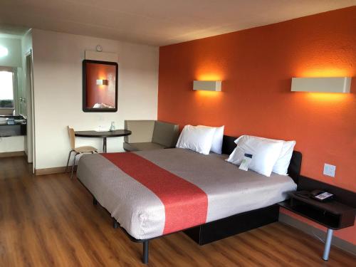 布伦瑞克Motel 6-Brunswick, GA的一间卧室配有一张带橙色墙壁的大床