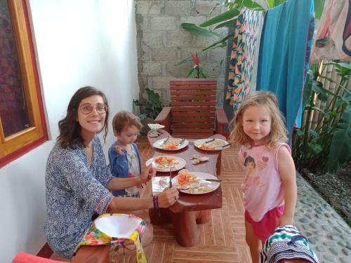 RiungRiung Guesthouse的坐在餐桌旁吃饭的女人和两个孩子