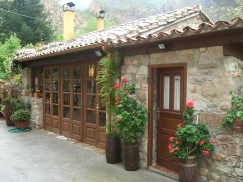 努埃瓦德兰斯Hotel rural La Llastra的一座带红色鲜花的木制车库的房子