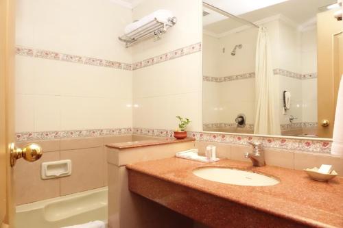 科钦阿巴德中庭酒店的浴室配有水槽、淋浴和浴缸。