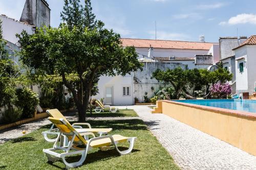 埃武拉Vintage Guest House - Casa do Escritor的一群椅子坐在游泳池附近的草地上