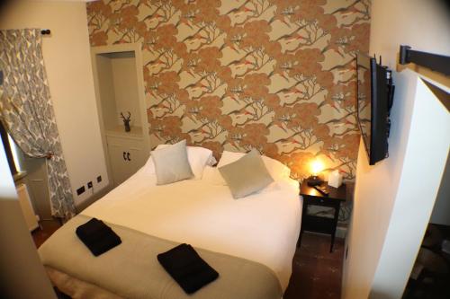 福尔柯克The Victoria Inn Blythswood Snug的一间卧室配有一张带花卉壁纸的床