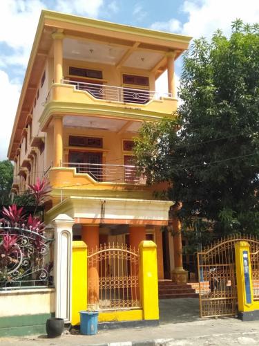 BaubauWisma Kahyangan的前面有栅栏的黄色房子