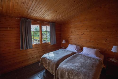米湖沃盖弗奥斯农场度假旅馆的小木屋内的两张床,设有窗户