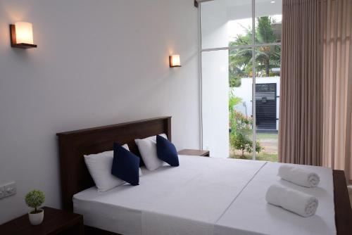 希克杜沃The Ritz Hikkaduwa的一间卧室配有一张带蓝色和白色枕头的床