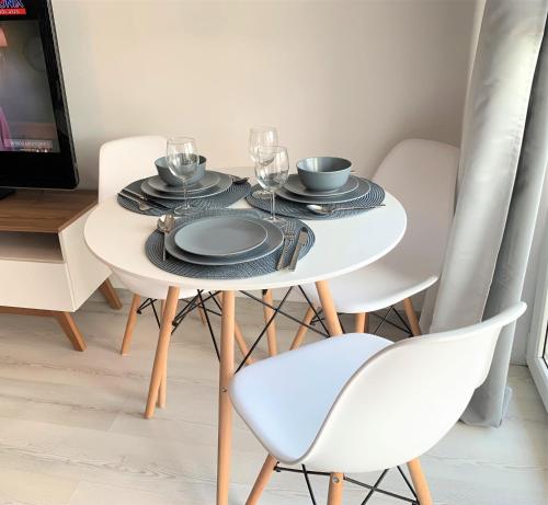马佐夫舍地区新庄园2-Room Apartment的一张带盘子和玻璃杯的白色桌子