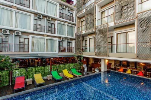 塞米亚克Horison Ultima Seminyak Bali - CHSE Certified的公寓大楼设有游泳池和多彩的椅子