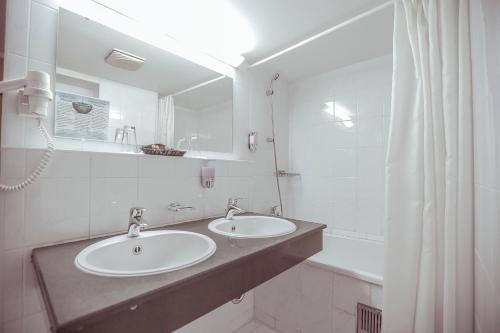 塔什干索德里克宫酒店的浴室设有2个水槽、镜子和浴缸。