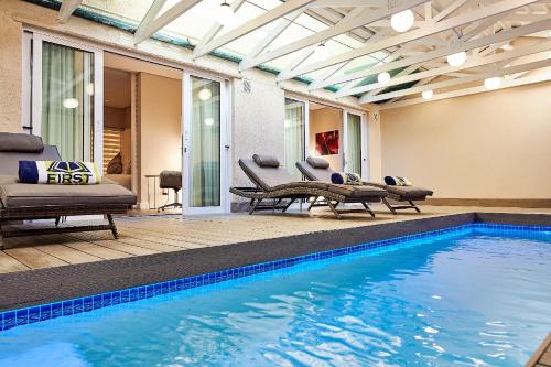开普敦First Group Riviera Suites的一座带椅子和桌子的别墅内的游泳池