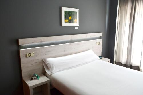 拉科鲁尼亚Alda Puerta Coruña的卧室配有白色的床和木制床头板