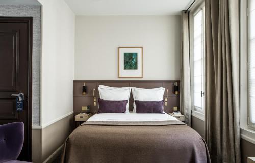 巴黎Hôtel La Tamise - Esprit de France的一间卧室配有一张带紫色枕头的大床