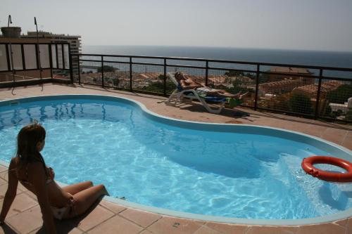 阿瓜杜尔塞阿瓜杜尔塞公寓酒店的坐在一个有海洋背景的游泳池里的女孩