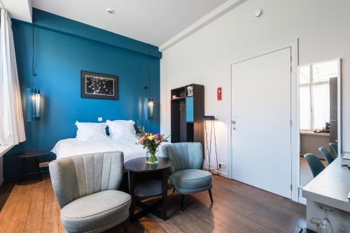 布鲁日Zakske13 - Design Boutique B&B in Bruges city centre的一间卧室设有蓝色的墙壁和一张带桌椅的床。