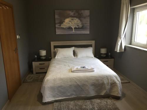 CabaçosCasa De Newsham的一间卧室配有一张带白色毯子和一棵树的床。