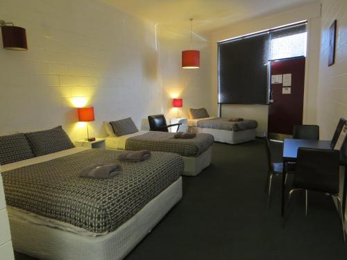 圣雷莫圣雷莫汽车旅馆的酒店客房带两张床和一张桌子以及椅子。
