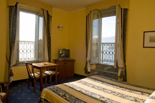 韦尔巴尼亚埃姆珀若酒店的酒店客房带两张床、一张桌子和两个窗户。