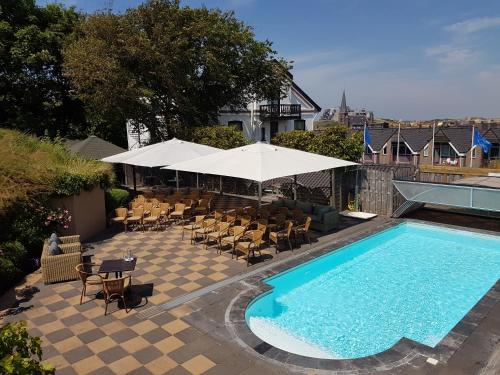 滨海韦克Boutique hotel Puur Zee - Adults Only的一个带椅子和桌子的游泳池以及一把遮阳伞