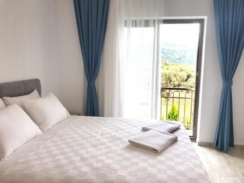 达特恰Oliva Casa Apart Hotel的一间卧室配有一张带蓝色窗帘的床和一扇窗户