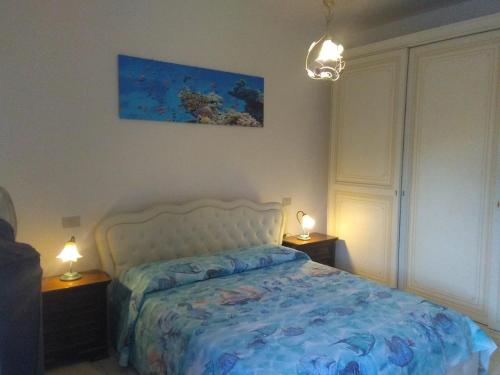 瓦达Blu Mariner的一间卧室配有一张带蓝色被子的床和两盏灯。