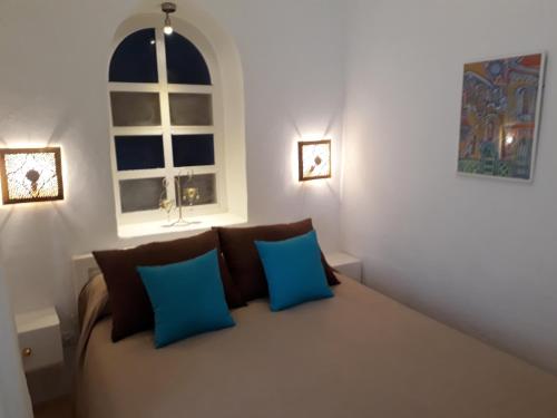 艾西拉Dar es Salam-Baja的客房设有带蓝色枕头的沙发和窗户。