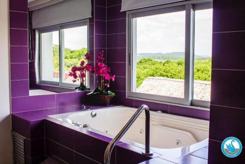 巴兰基亚Hotel Campestre El Cisne的紫色浴室设有浴缸和窗户