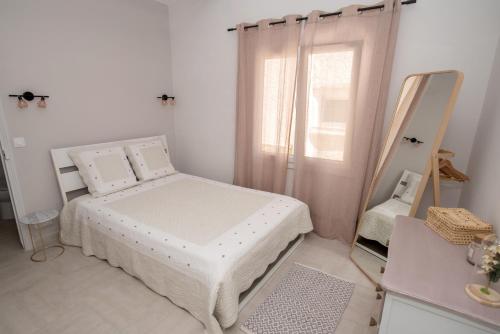 圣特罗佩Charmante petite maison a l'éntrée de Saint Tropez的白色卧室配有床和镜子