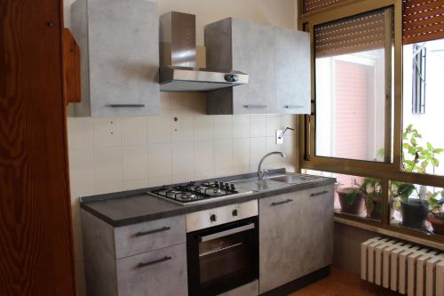 韦列Appartamento Galileo的厨房配有炉灶、水槽和窗户。
