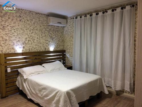 弗洛里亚诺波利斯Residencial Dona Preta的一间卧室配有一张带白色床单和窗帘的床