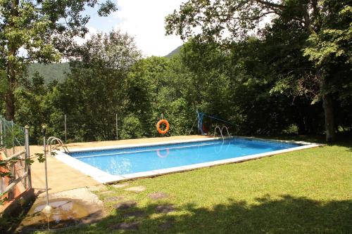 圣胡安-德拉斯阿巴德萨斯野营阿巴德斯酒店的一座大游泳池,位于一个树木繁茂的庭院内