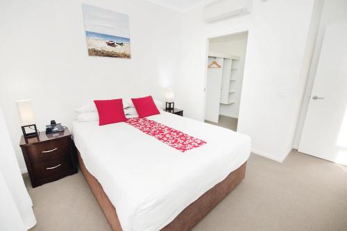 格拉德斯通Curtis Central Apartments Official的卧室配有带红色枕头的大型白色床