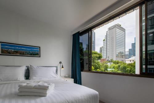 曼谷Every Surawong的卧室设有白色的床和大窗户