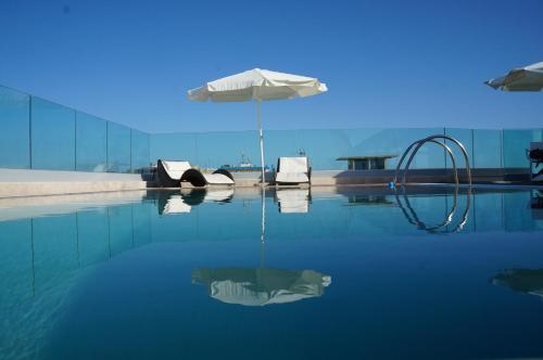 安齐奥阿普罗多酒店的一个带遮阳伞和椅子的水池