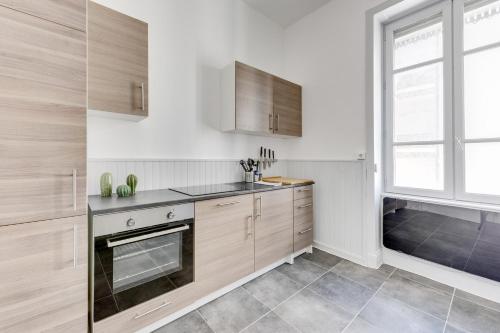 里昂NOCNOC - L'Escapade的厨房配有木制橱柜和窗户。