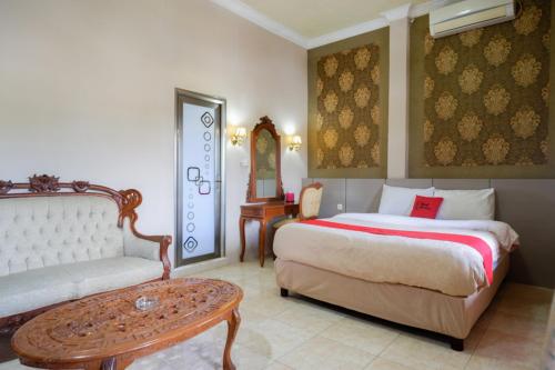 肯达利RedDoorz Plus at Hotel Srikandi Kendari的一间卧室配有一张床、一张沙发和一张桌子