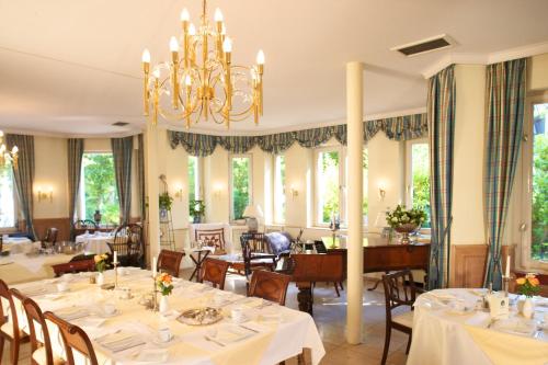 梅尔布施Hotel Villa Meererbusch的一间带桌椅和吊灯的用餐室