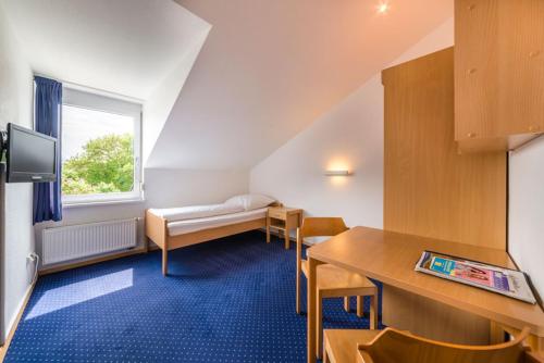 腓特烈港CAP罗塔奇酒店的配有一张床和一张桌子及椅子的房间
