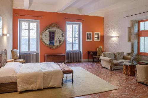 Caunes-MinervoisHôtel Restaurant d'Alibert的一间卧室拥有橙色的墙壁,配有一张床和一张沙发