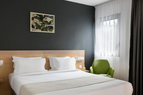巴黎馨乐庭奥斯特利兹巴黎酒店的一间卧室配有一张床和一把绿色椅子