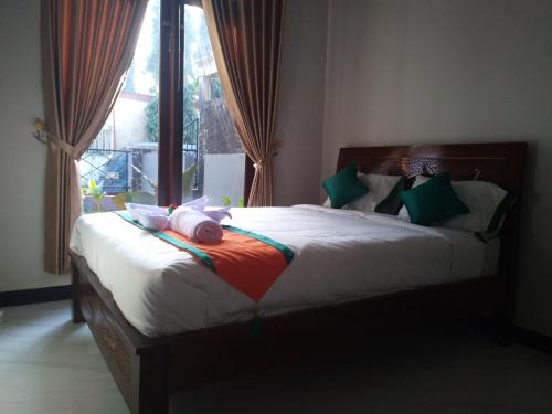 PurbolinggoHomestay Purbalingga Tengah Kota by Simply Homy的一间卧室配有一张带绿色和红色枕头的大床